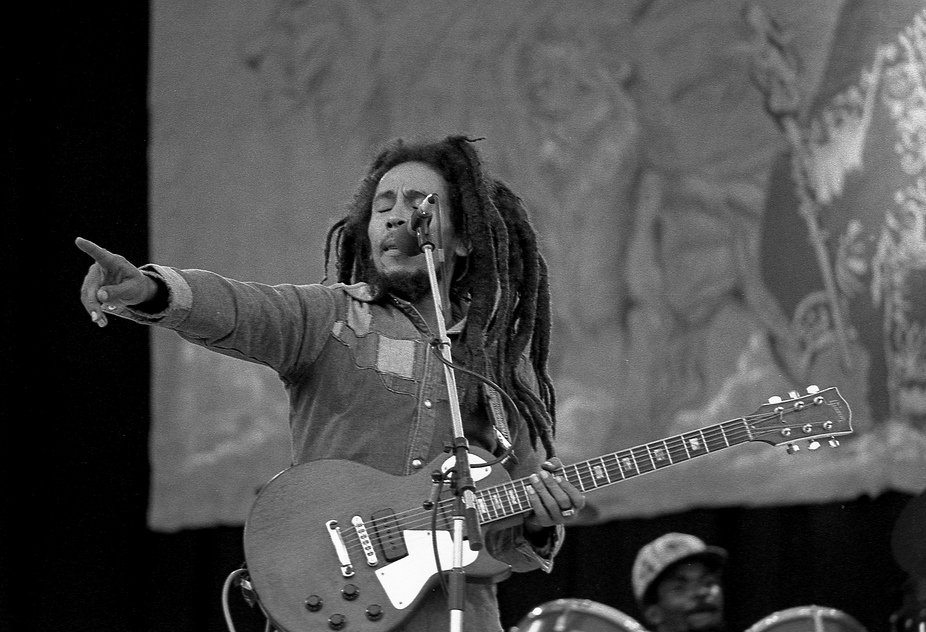 Bob Marley cantando e tocando guitarra em palco de show