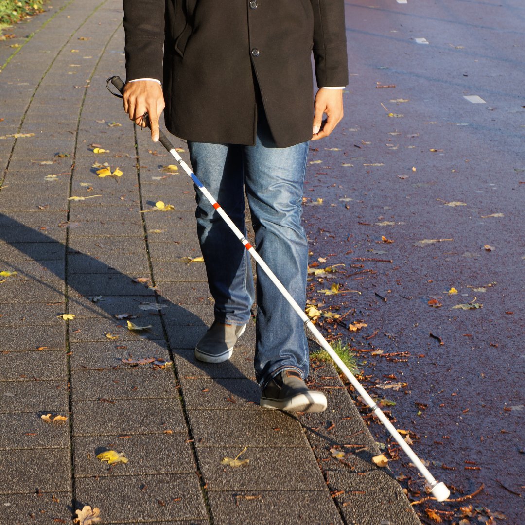 Imagem de uma pessoa cega caminhando com sua bengala