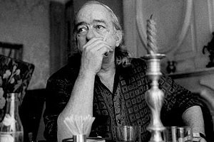 Vinicius de Moraes em foto preta e branca em mesa fumando cigarro