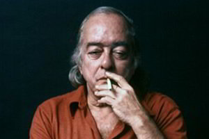 Vinicius de Moraes fumando cigarro visto de frente em fundo preto