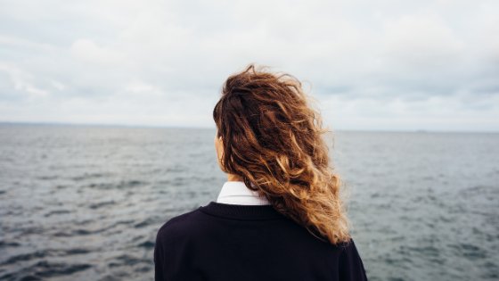 Mulher olhando para o mar a sua frente
