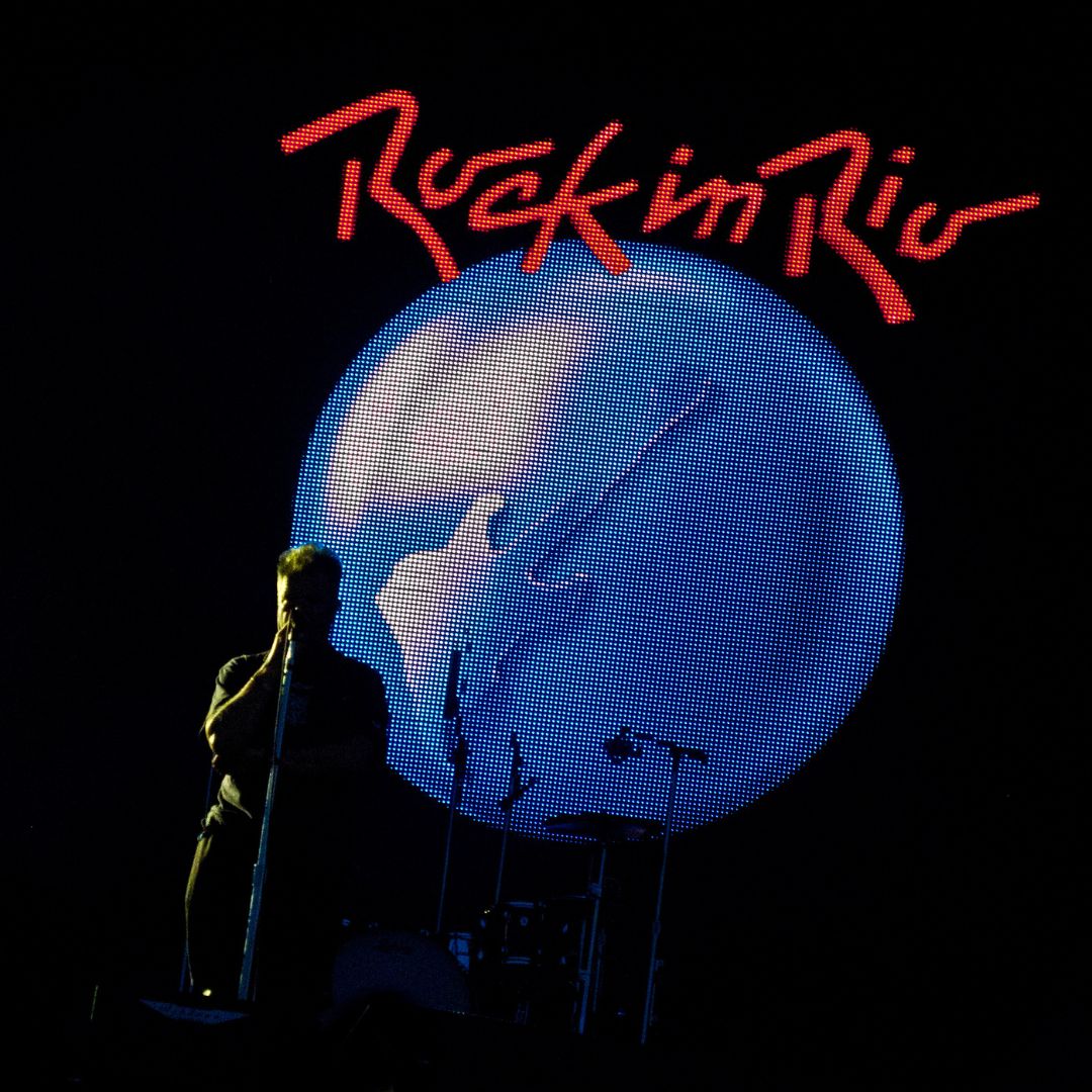 Wikimedia Commons Silhueta de um cantor cantando em frente ao logo oficial do Rock in Rio