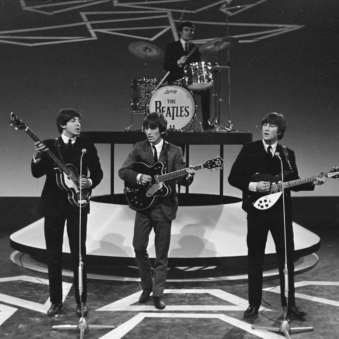 Imagem em preto e branco dos Beatles tocando em um programa de televisão