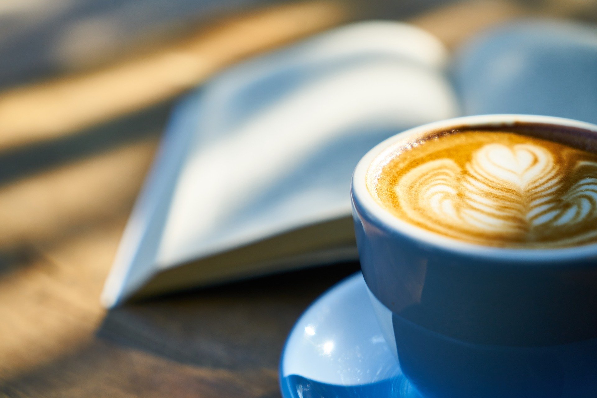 Livro aberto ao lado de uma xícara com café