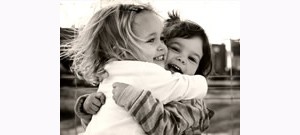 Duas crianças abraçadas e sorrindo.