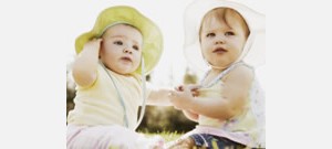 Dois bebês sentados juntos, usando chapeus.