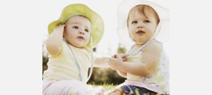 Mensagens Com Amor Dois bebês sentados juntos, usando chapeus.