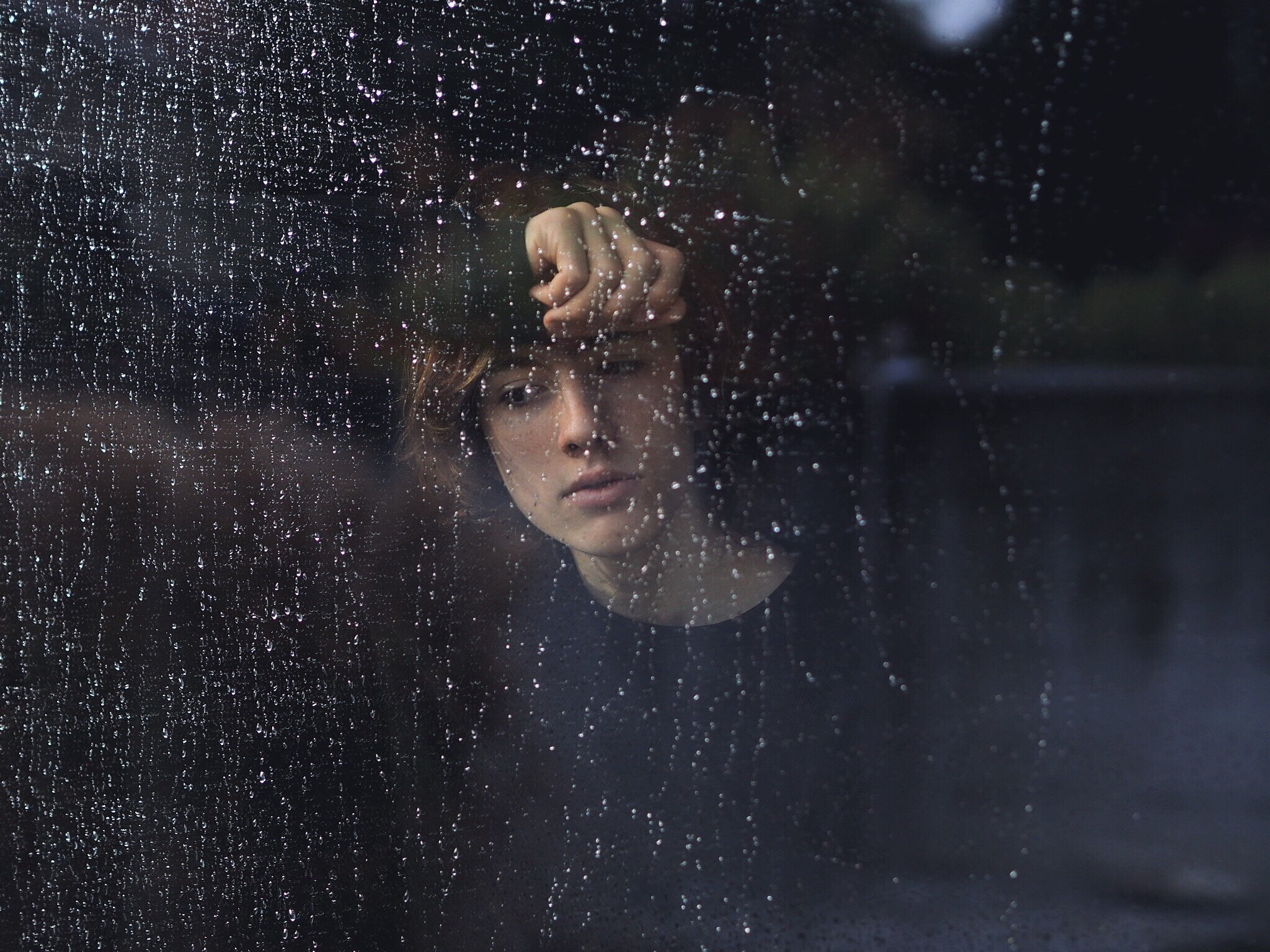 Mulher na janela observando a chuva