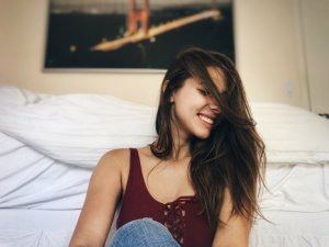 Julia/Reshot Mulher sentada no chão ao lado da cama sorrindo