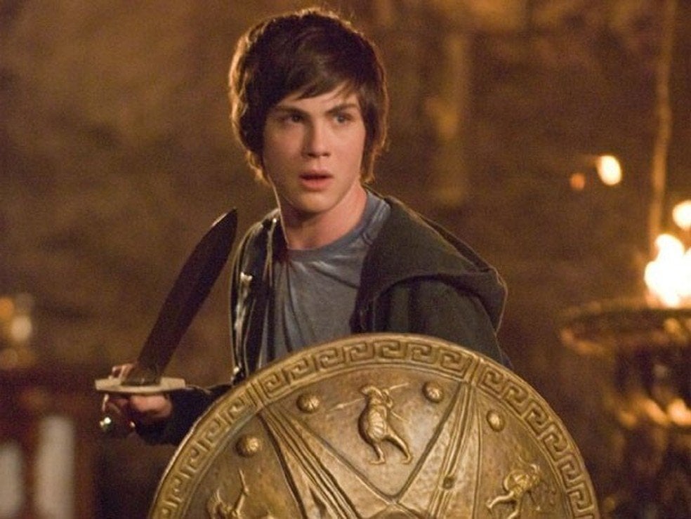 Personagem Percy Jackson em cena segurando espada e escudo
