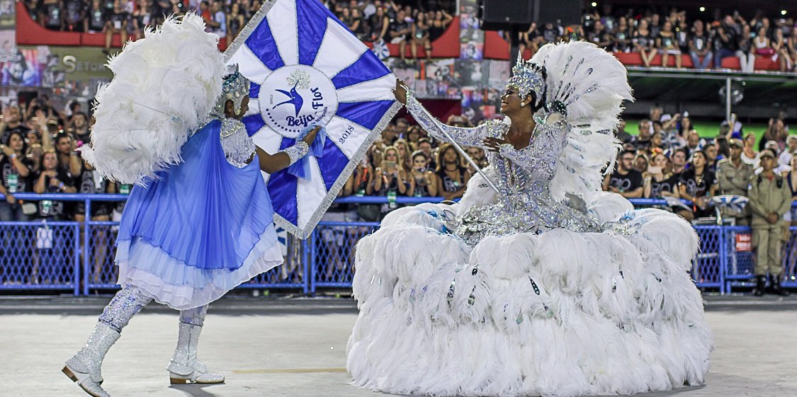 Dançarinos da escola de samba segurando bandeira
