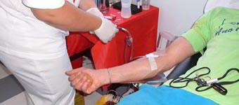 Técnico de enfermagem manipulando agulha em braço de paciente.