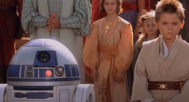 Personagem Anakin Skywalker da saga Star Wars ao lado de um robô e crianças ao fundo