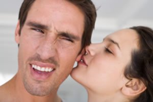 Mulher dando beijo em orelha de homem
