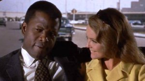 Reprodução/Columbia Pictures Os atores Sidney Poitier e Katherine Houghton sentados no banco de trás de um carro, com a mulher olhando para o homem.
