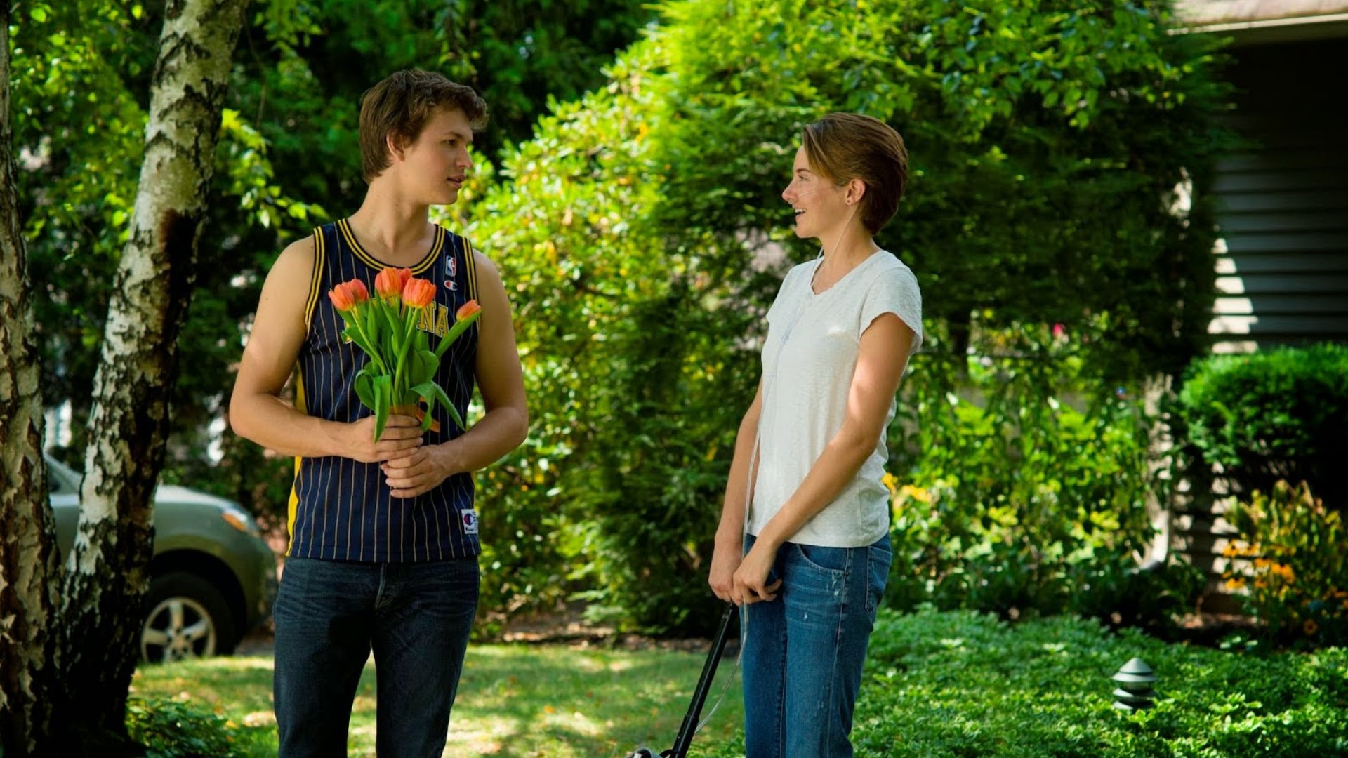 Gus segurando flores conversando com Hazel no jardim