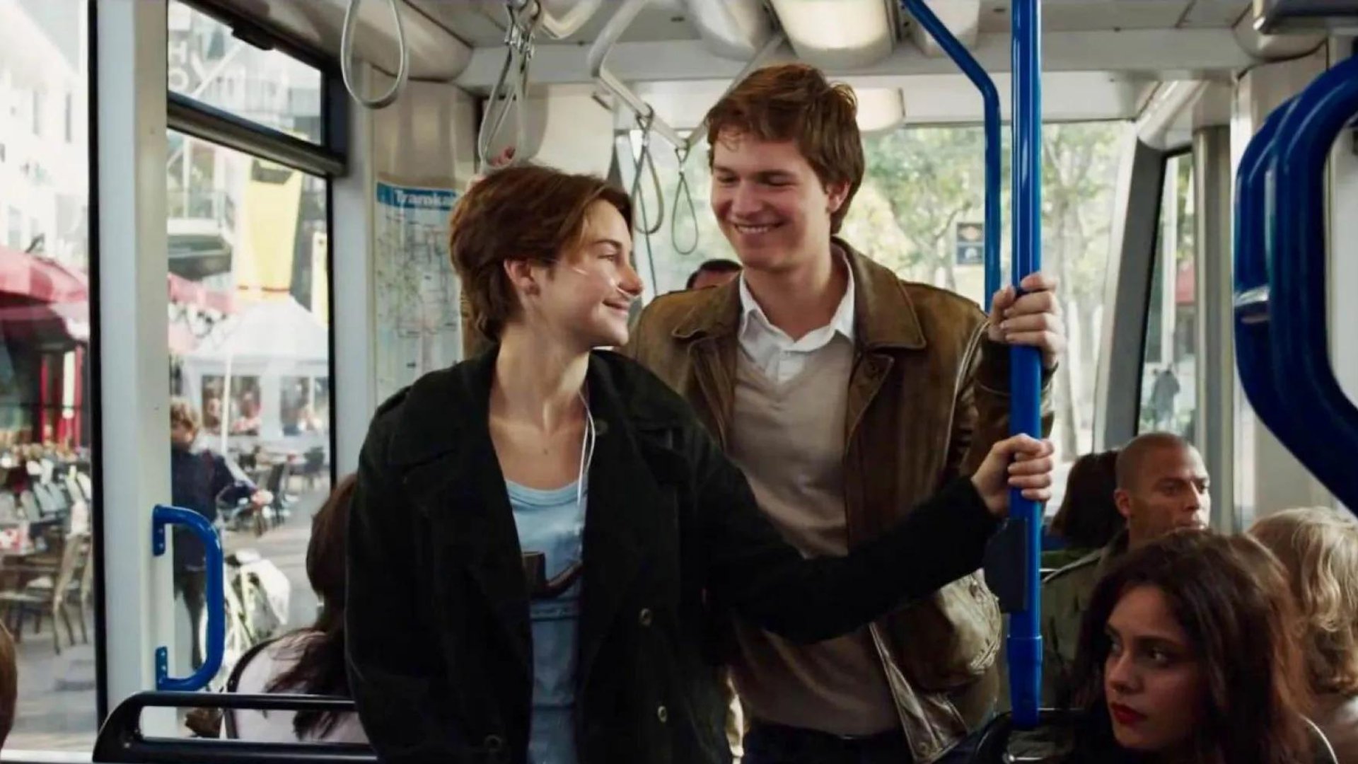 Hazel e Gus sorrindo enquanto andam de ônibus