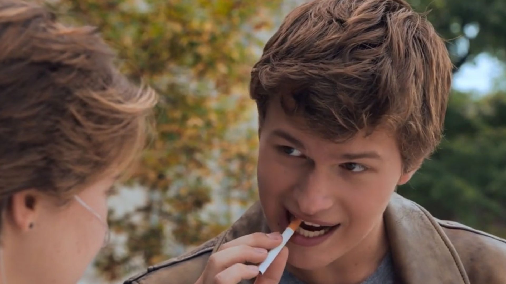 Augustus olhando para Hazel enquanto bota um cigarro na boca