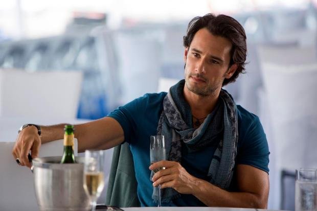 Rodrigo Santoro segurando taça de champanhe em cena do filme 'Golpe Duplo'.