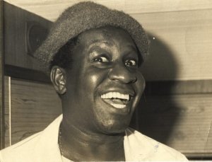 maisminas.org Mussum usando chapéu e sorrindo em foto preto e branco