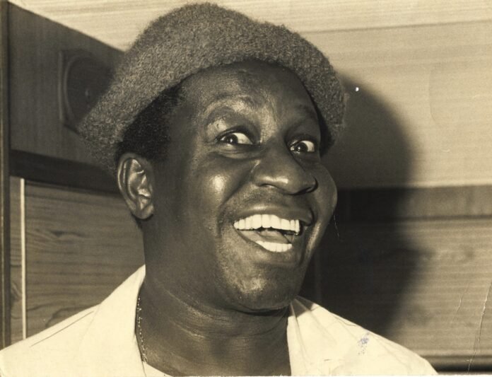 Mussum usando chapéu e sorrindo em foto preto e branco