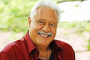 Fotografia de Antônio Fagundes de camisa vermelha aberta e sorrindo