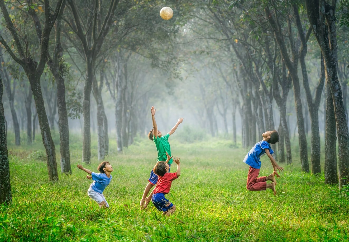 Unsplash/Robert Collins Crianças brincando com uma bola em um parque.