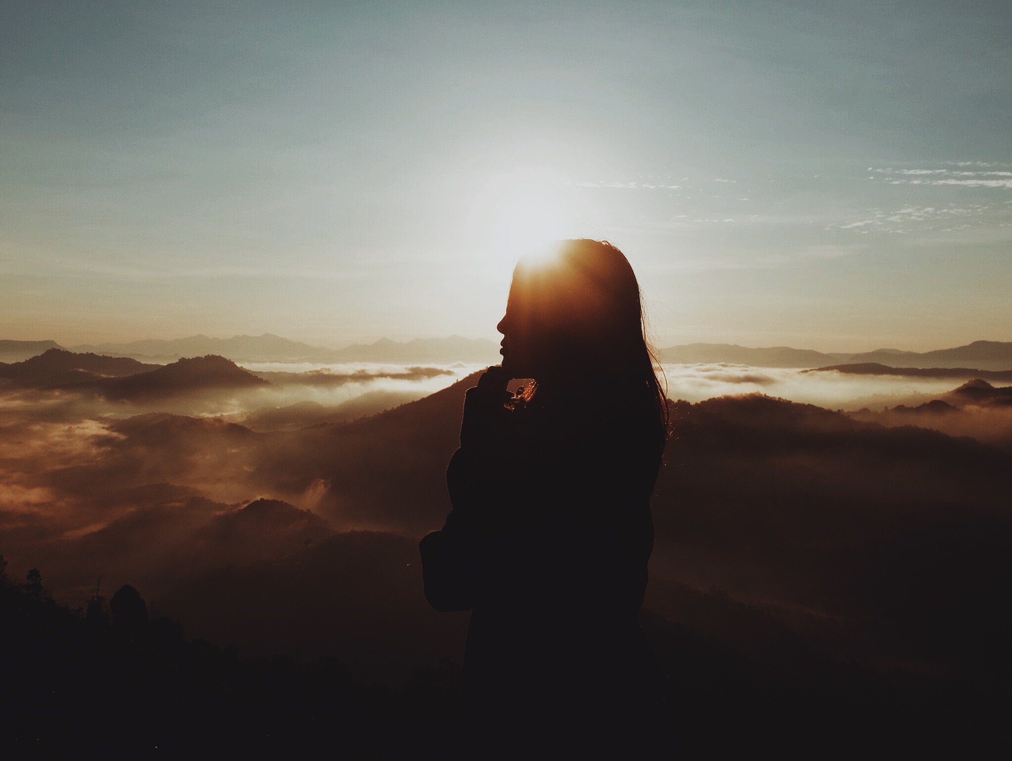Silhueta de mulher em uma montanha e pôr do sol