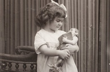 Frida quando criança segurando uma boneca em seus braços