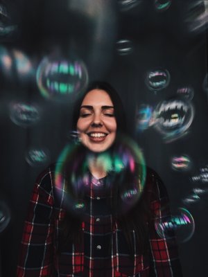 Irina Milevskaya em Reshot Mulher sorrindo com os olhos fechados com bolhas de sabão ao seu redor