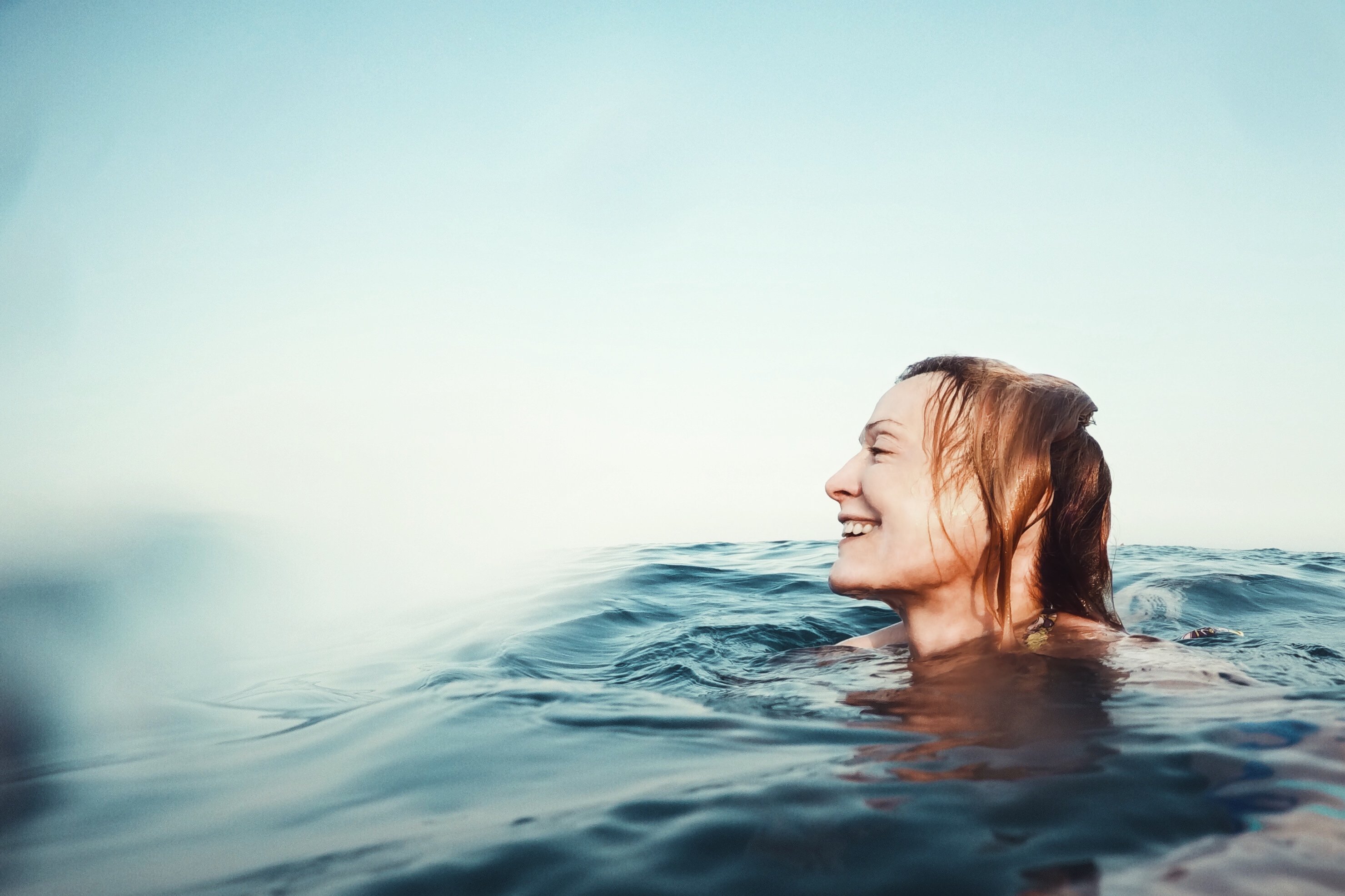 Mulher sorrindo nadando no mar