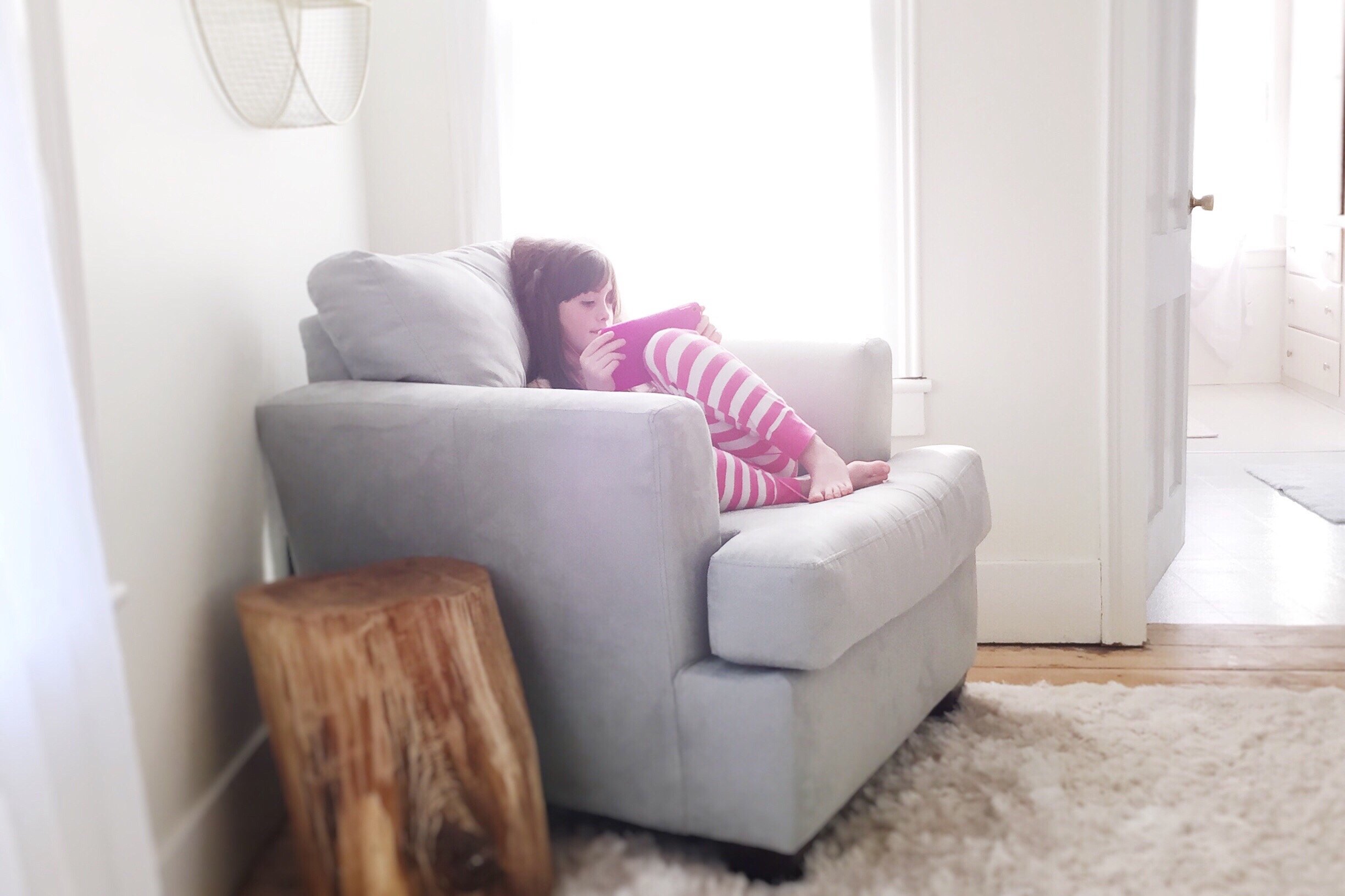 Criança sentada no sofá segurando um tablet