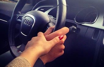 Mulher segura mão de homem enquanto ele dirige.