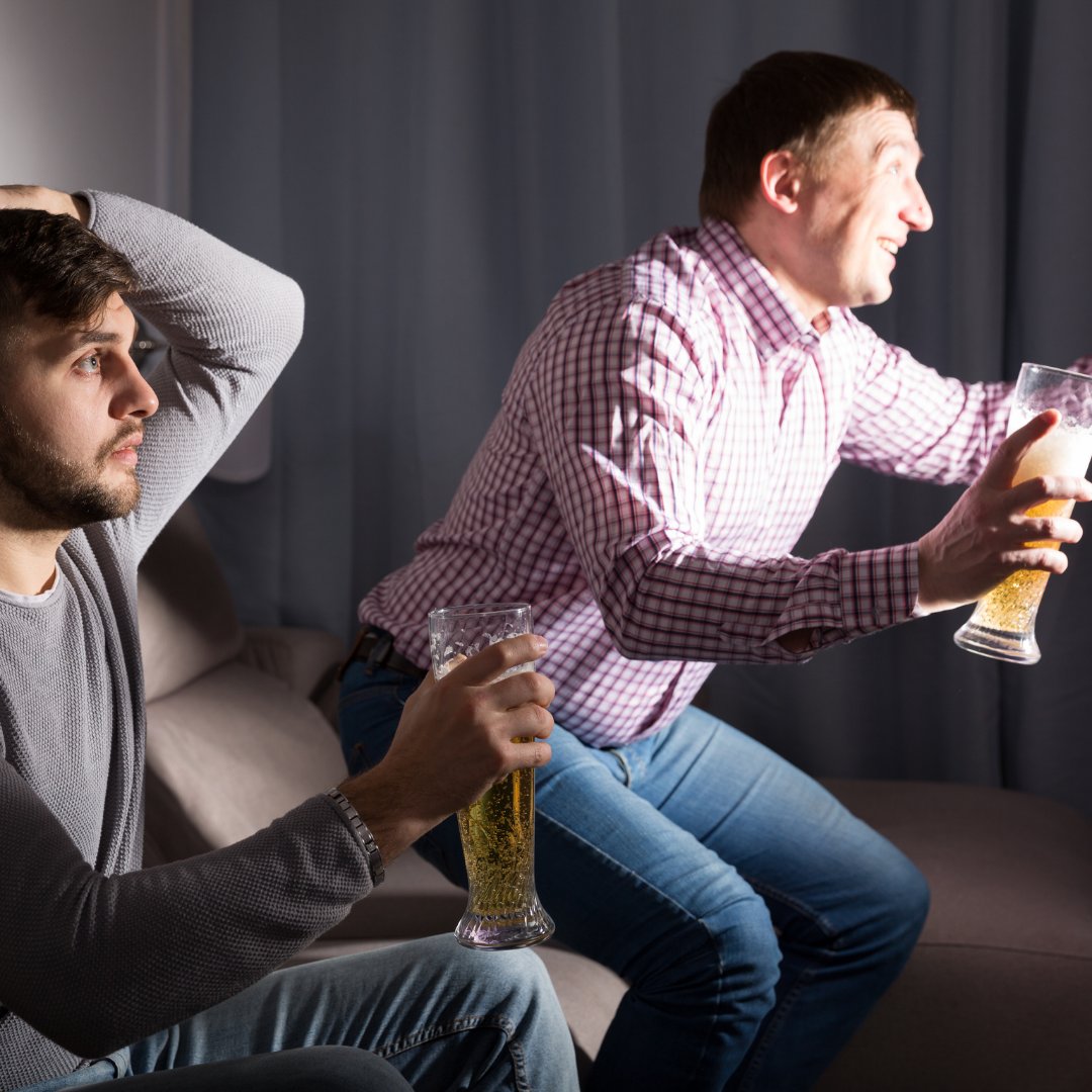 Imagem de dois homens tomando cerveja e assistindo jogo juntos