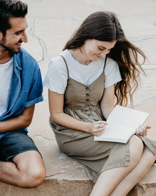 Homem olha para mulher enquanto ela lê um livro