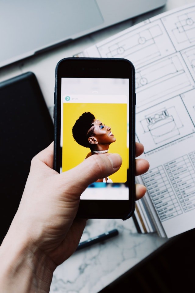 Pexels/ready made Pessoa segurando um celular que mostra da foto de uma mulher em uma rede social