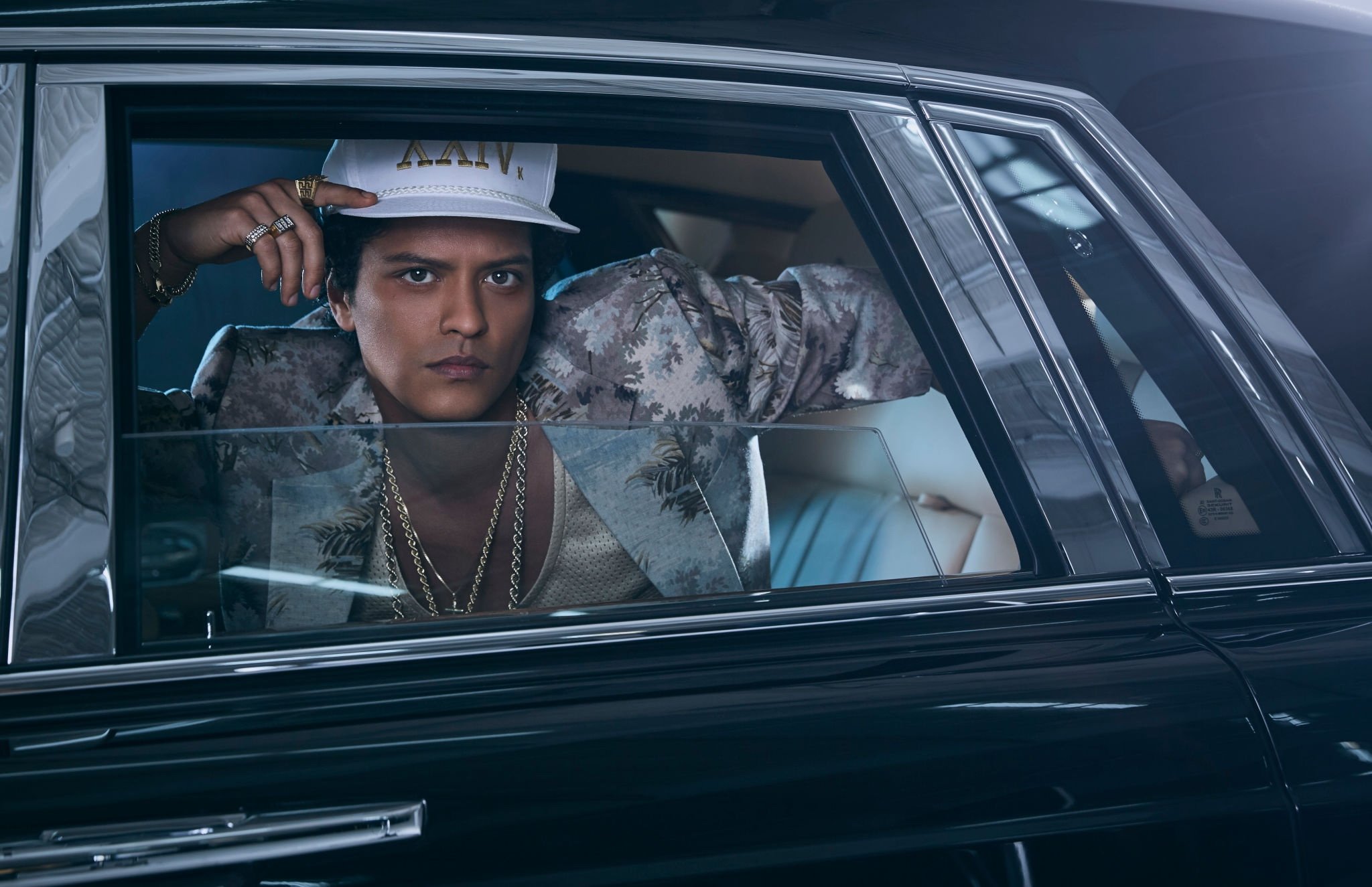 Bruno Mars dentro de carro, posando para foto pela janela traseira.