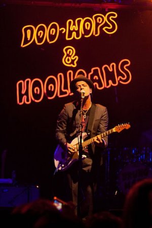 Wikipedia - Brothers Le Bruno Mars se apresentando em show, cantando e tocando guitarra.
