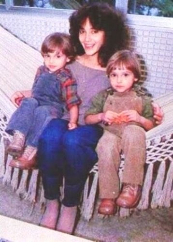 Cristiane Torloni com seus dois filhos sentada em uma rede.