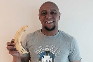 Roberto Carlos, ex-jogador da seleção brasileira em foto com banana na mão sorrindo.