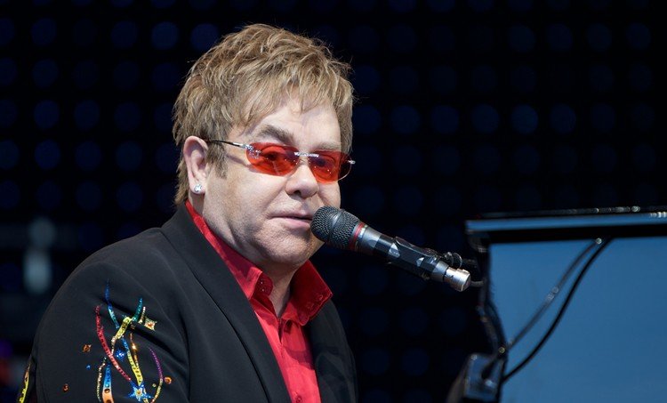 Elton John em show cantando e tocando piano