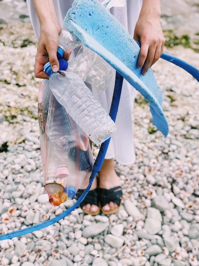 Pessoa segurando lixos plásticos encontrados na praia.