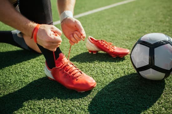 Jogador de futebol amarrando a chuteira no campo