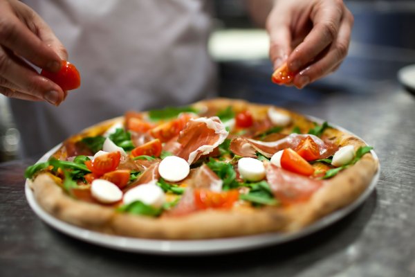123RF/ denizo71 Pessoa colocando ingredientes em uma pizza