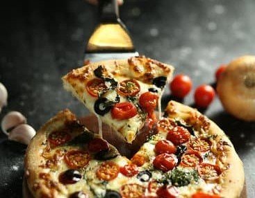 Hoaluu/Canva Pessoa retirando pedaço de pizza com espátula