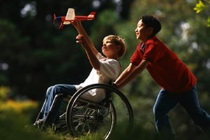 Criança empurrando outra criança cadeirante com avião de brinquedo na mão
