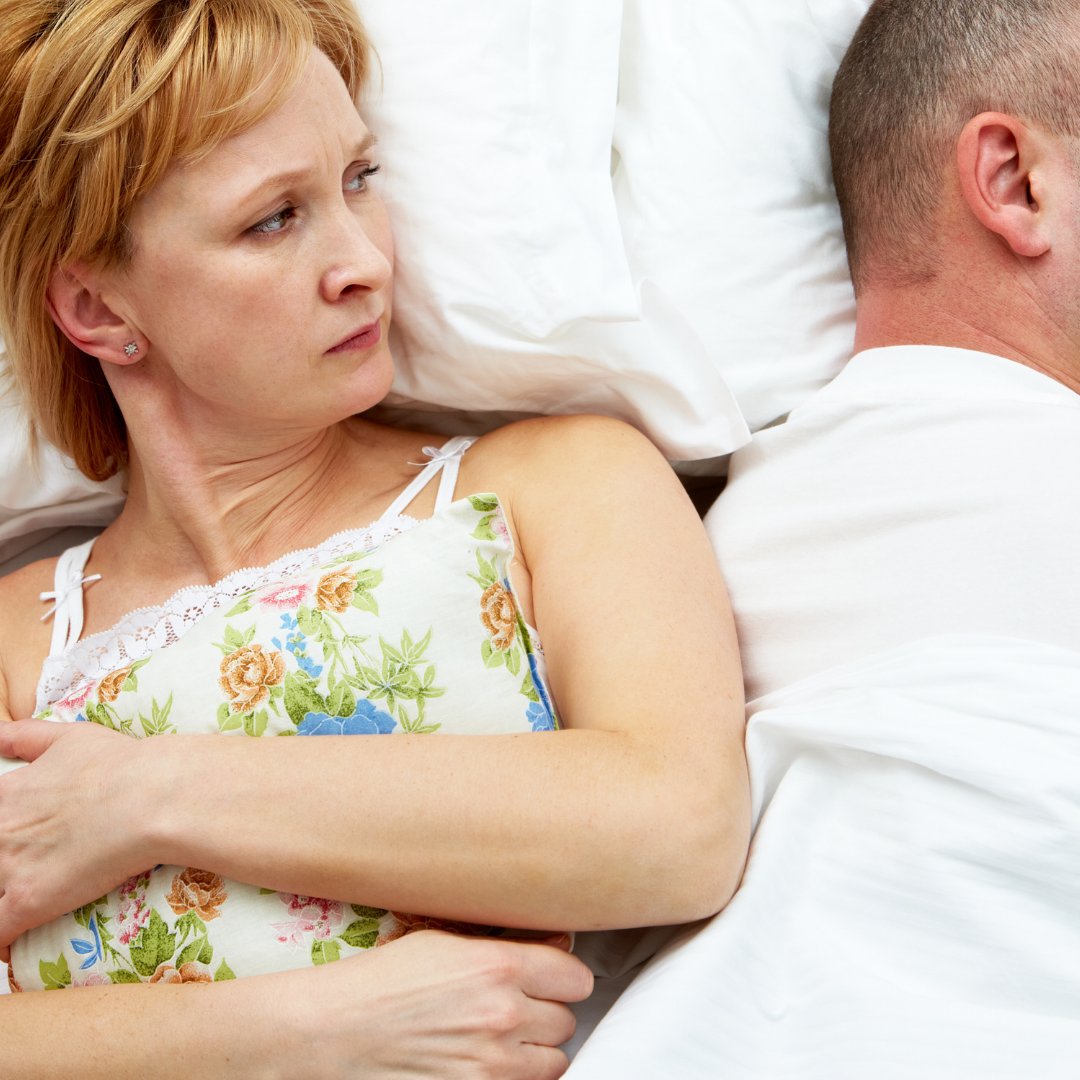 Mulher irritada olhando para o marido na cama