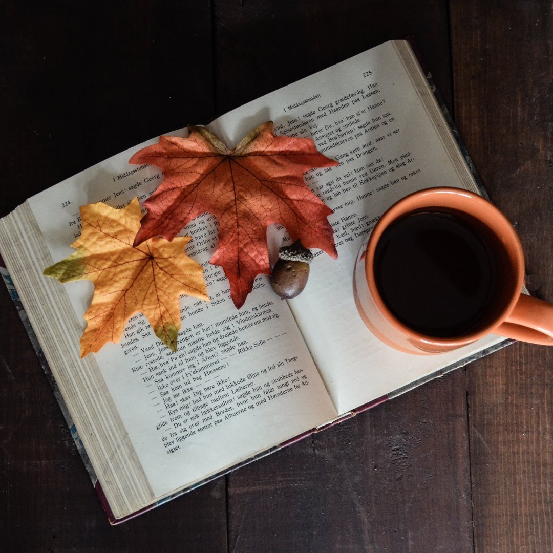 Livro aberto com folhas de outono e uma xícara de café