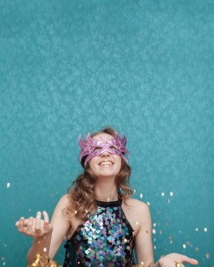 Freepik Mulher com máscara de carnaval jogando confetes para o alto.