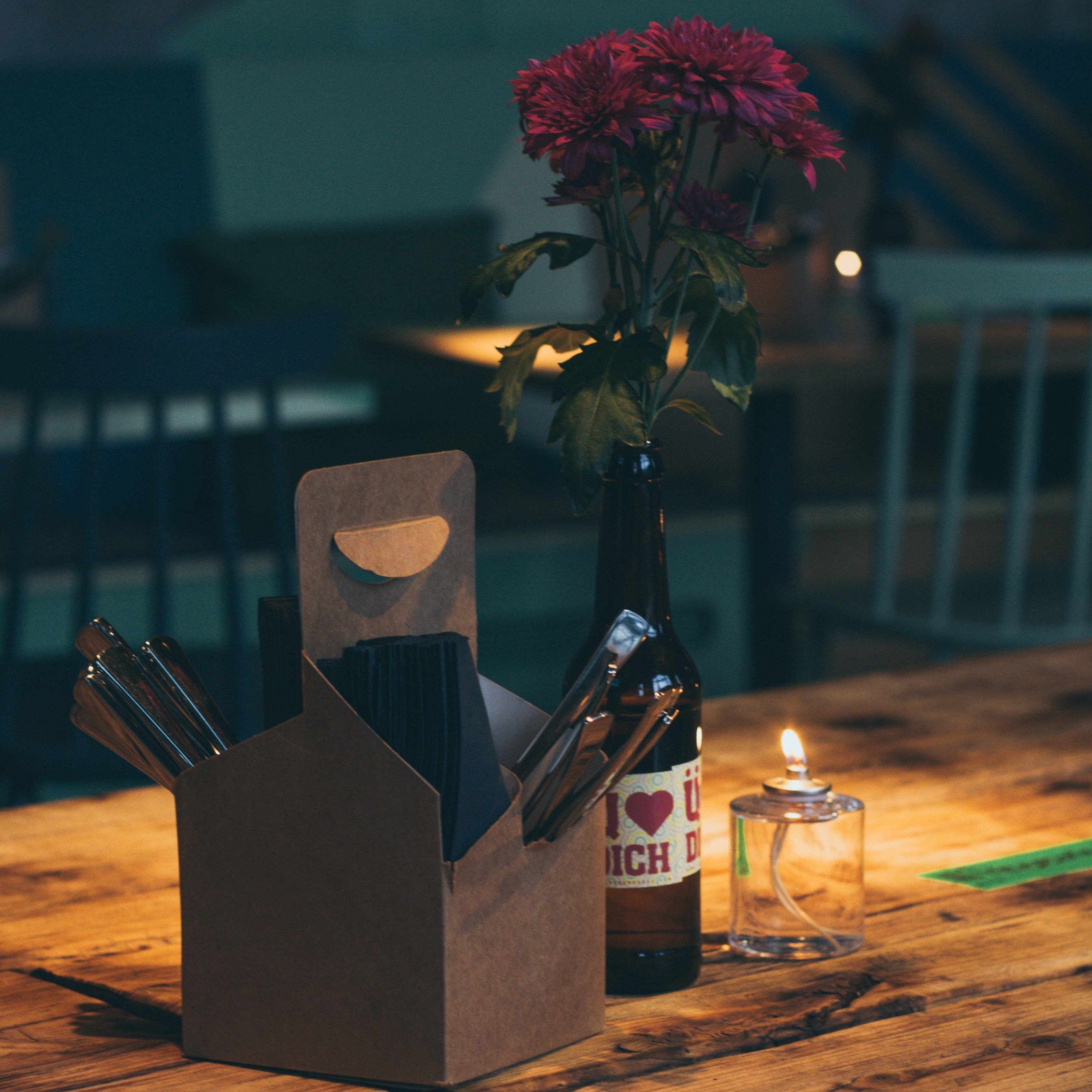Mesa com vela, garrafa com flores e uma caixa de comida japonesa
